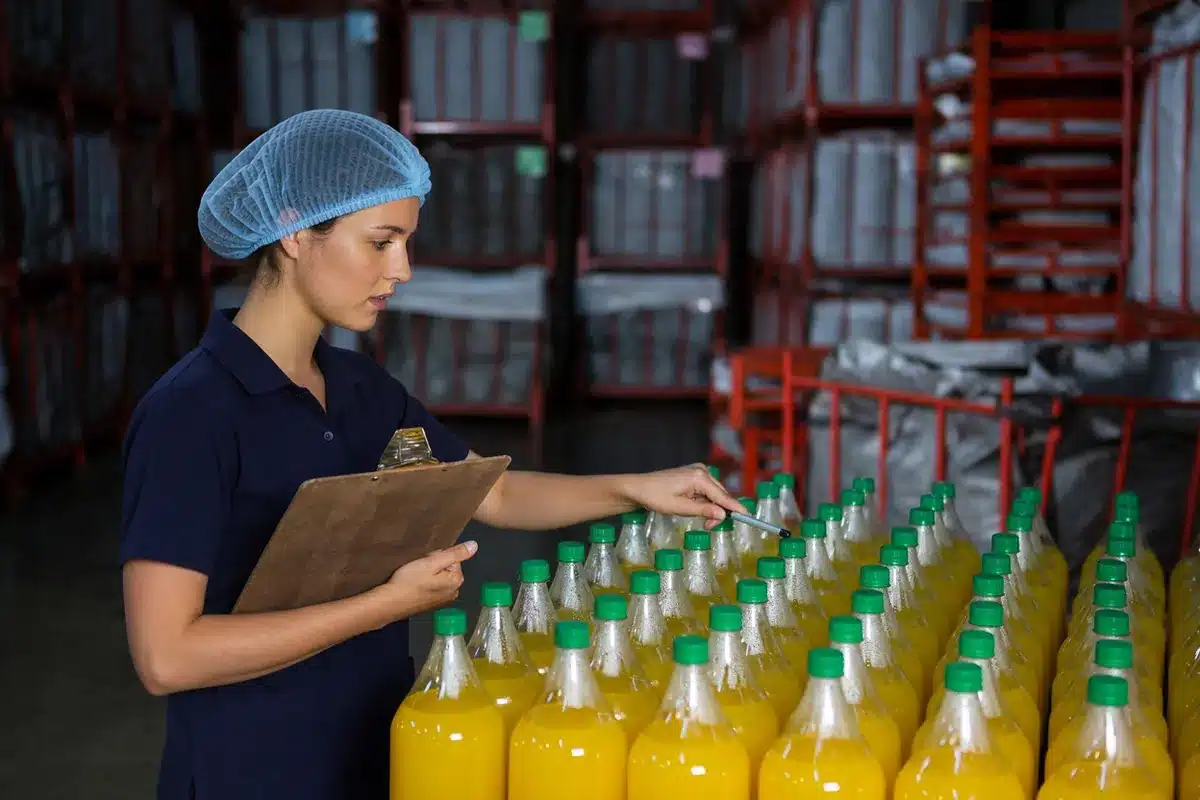 Encargada con redecilla y tabla revisa un lote de bebidas envasadas en la bodega de una distribuidora de alimentos en Guatemala.